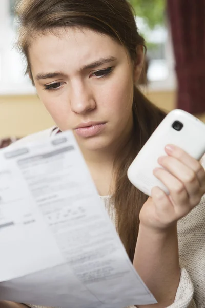 Tonårig flicka studerar mobiltelefon Bill ser orolig — Stockfoto