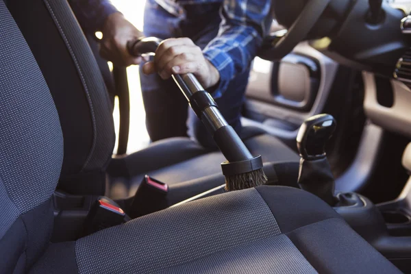 Man Hoovering zetel van de auto tijdens het reinigen van de auto — Stockfoto