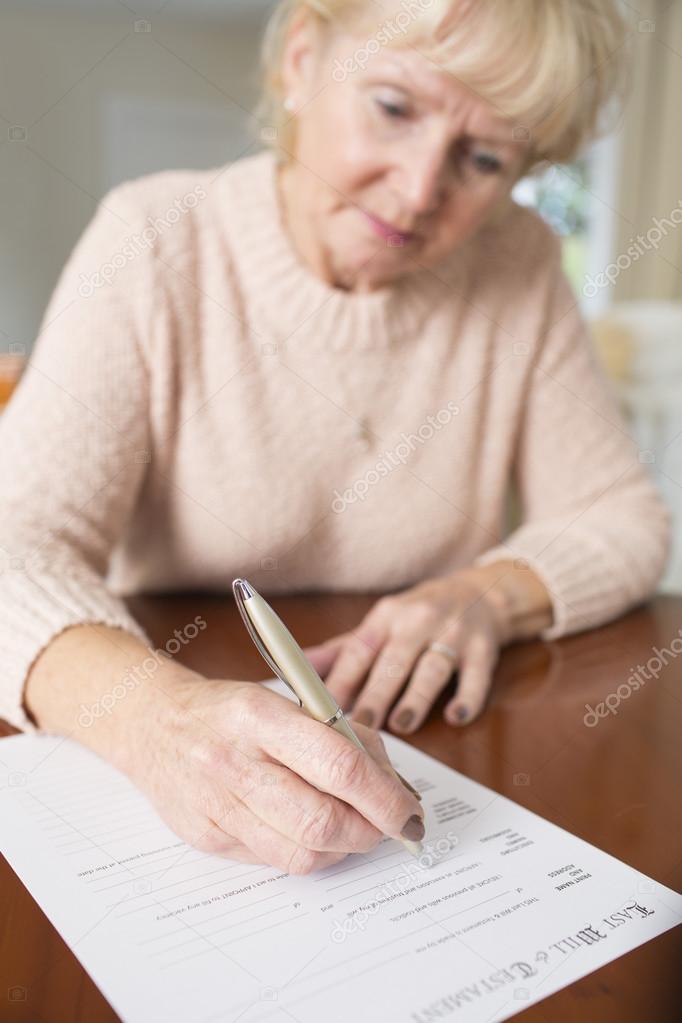 Senior Woman Signing Last Will And Testament At Home