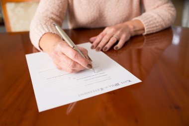 Senior Woman Signing Last Will And Testament At Home clipart