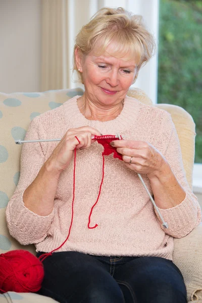 Senior vrouw zitten In de stoel breien — Stockfoto