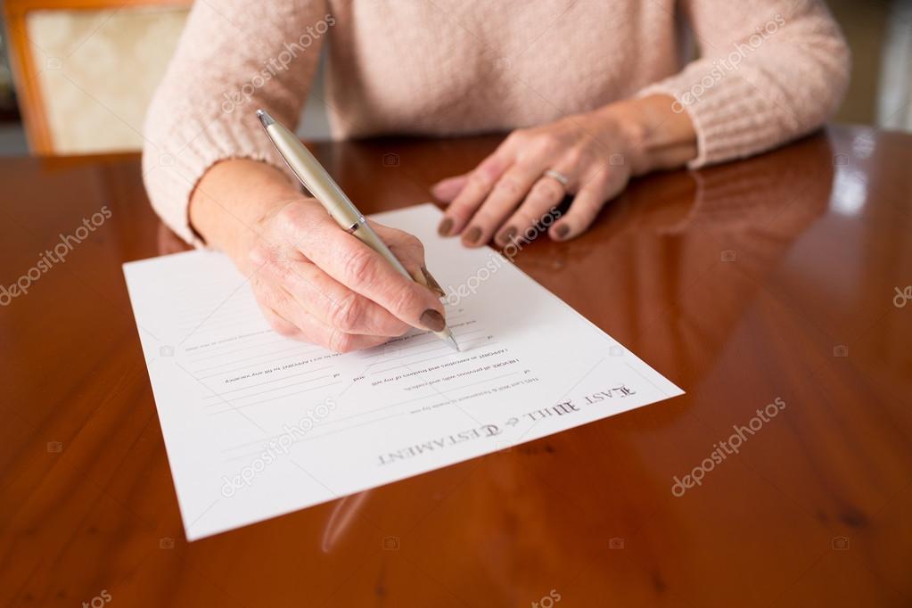 Senior Woman Signing Last Will And Testament At Home