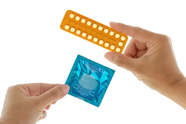 A hand holding package of condom in exchange with birth control pills — Stock Photo, Image