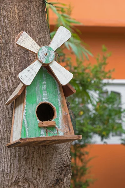 Деревянный птичий домик с настоящим птичьим гнездом внутри, висящим на манго — стоковое фото