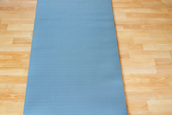 Anti slip mavi fitness yoga pratik veya meditasyon mat ahşap zemin üzerinde kalın — Stok fotoğraf