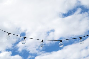 Büyük yuvarlak mavi bulutlu gökyüzü arka plan ile havada asılı Lightbulbs