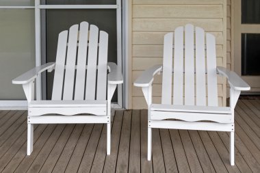 Two white wooden adirondack chair on old weathered front porch clipart