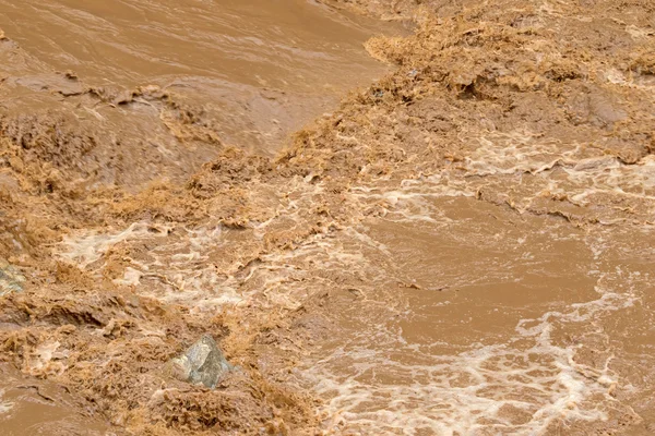 Närbild av snabba flödet av brunt vatten i floden muddy — Stockfoto