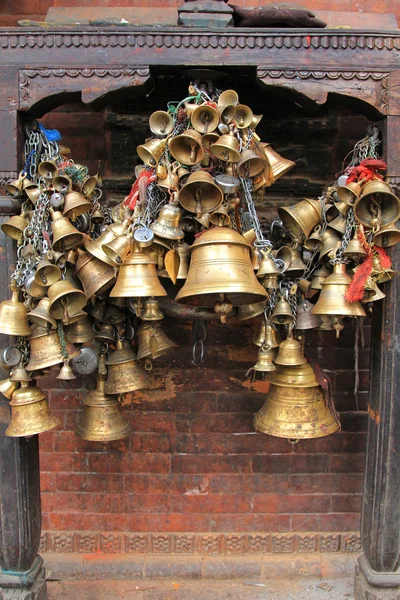 Metal sacrificial bells hanging on chain at Kumbeshwar Temple in Nepal — Stock Photo, Image