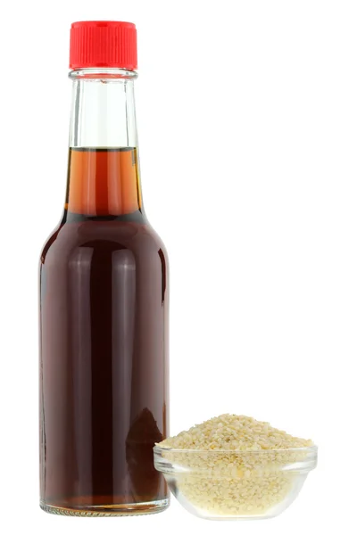 Sesame oil next to a bowl of white Sesame seeds — Stock Photo, Image