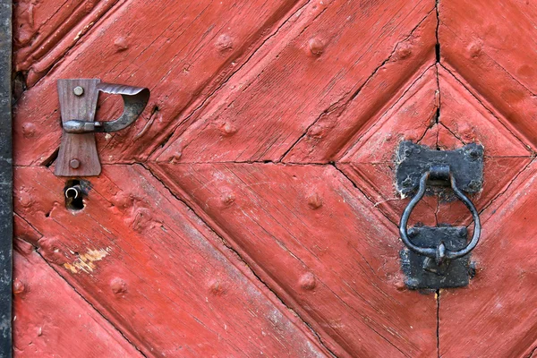 Red wooden door with rustic keyhole, doorknob, door knocker — Stock Photo, Image