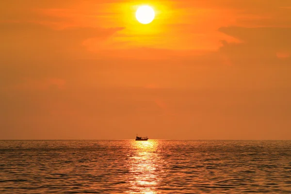 Foto puesta de sol con una silueta de un barco flotando en el reflejo del sol — Foto de Stock