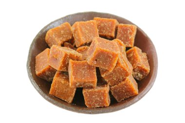 A bowl full of blocks of dark brown sugar made of cane sugar clipart