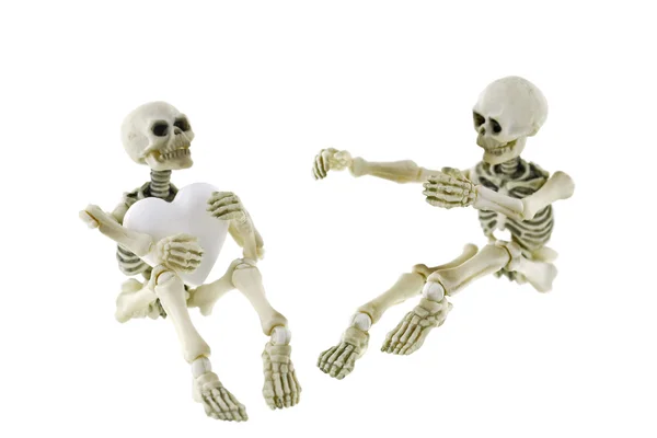 Skeletons sitting together with one holding a white heart — Stock Photo, Image