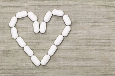 White tablets in a heart shaped symbol with copyspace  clipart