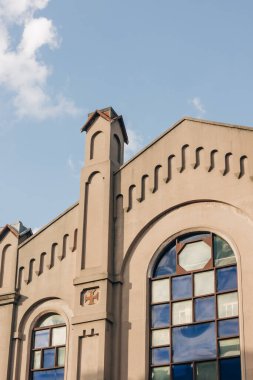 Bu sahnede, parlak mavi gökyüzüne karşı karmaşık tasarım unsurları sergilenen tarihi bir bina yer alıyor..