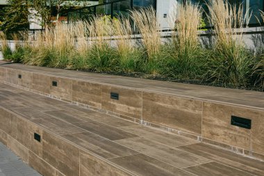 İyi tasarlanmış bir teras, tahta görünümlü fayanslar ve uzun otlar içerir. Gündüz vakti modern bir açık hava alanı yaratır..