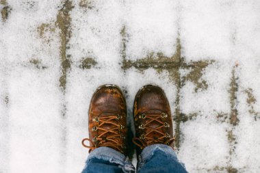 Sıcak kahverengi çizmeler, karlı bir yüzeyde dinleniyor. Buz ve sükunetle dolu bir kış manzarası sergiliyorlar..