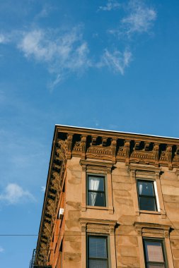 Karmaşık detaylara sahip eski bir bina, klasik mimari tarzını yansıtan parlak mavi bir gökyüzüne karşı duruyor..