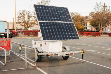 Bir seyyar güneş enerjisi istasyonu açık bir öğleden sonra güneş ışığını kullanarak bir otoparkta duruyor..