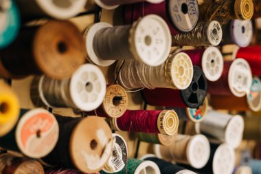 Renkli iplik makaraları bir rafta sergileniyor, rahat bir zanaat odasında çeşitli dikiş projeleri için hazır..