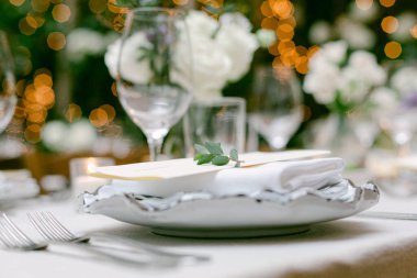 Çatal bıçak takımları ve çiçek süslemeleriyle hassas tabak düzenleme, toplanma için neşeli bir ruh halini ön plana çıkarıyor..