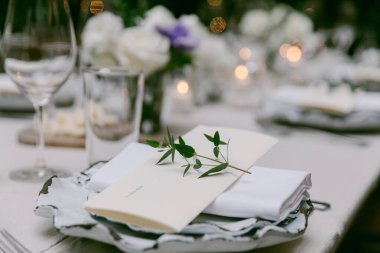 Güzel düzenlenmiş bir masa, mumları, çiçekleri ve akşam toplantısı için detaylı yer ayarlarıyla misafirleri bekliyor..