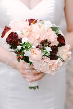 Gelin elinde pembe ve kırmızı çiçekli güzel bir buket tutuyor. Romantik bir düğün için mükemmel..