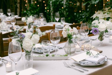 Çiçek ve mumlarla süslenmiş güzel masalar açık hava akşam yemeği için romantik bir ortam yaratır..