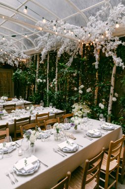 Masalar çiçeklerle ve mumlarla güzelce düzenlenmiştir. Samimi bir bahçe alanında özel bir etkinlik için mükemmeldir..