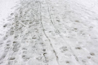 Ayak izleri ve lastik izleri karların üzerinde görülebilir kışın kentsel bir bölgede..