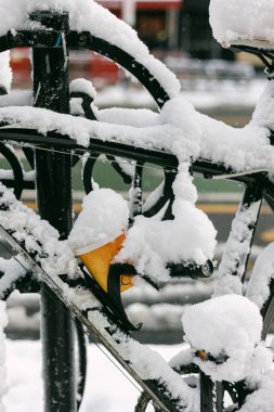 Bisiklet parkında durağan bir bisiklet. Şehirde kış günü kar motosikletin parçalarını kaplıyor..