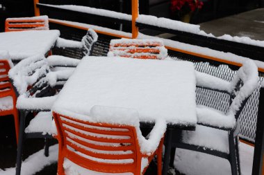 Soğuk kış mevsiminde kar yağarken bir restoranda beyaz kar örtüleri mobilyaları boşaltır..