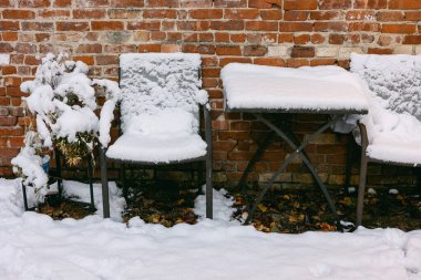 Kar battaniyeleri iki sandalye ve tuğla duvarın yanında bir masa kış boyunca sessiz bir açık alanda..