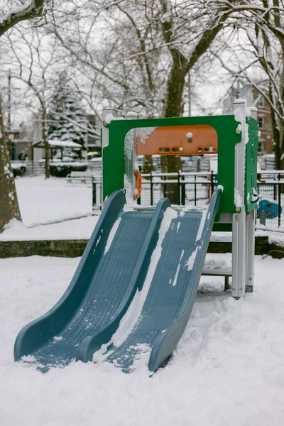 Kar, çocuklar bir kış günü bir parkta oynarken oyun parkı ekipmanlarını kaplıyor..