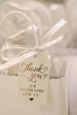 Hediye çantası bir teşekkür notu gösteriyor. Arkadaşlarıyla ya da aileleriyle bir kutlama etkinliği için gümüş kurdeleyle bağlanmış..