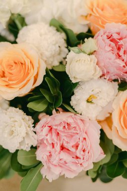 Bir bukette pembe, turuncu ve beyaz renkte bir grup çiçek bir masanın üzerinde güzel bir görüntü oluşturur..