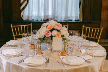 Öğleden sonra kapalı bir mekanda yapılacak toplantı için çiçeklerle ve camlarla dolu bir masa hazırlanır..