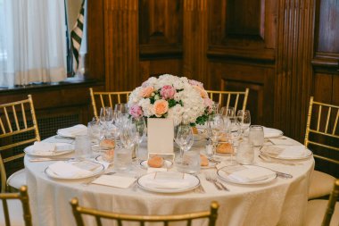 Masa bir etkinlik sırasında yemek için bardaklar, tabaklar ve ortada bir çiçek görüntüsüyle kurulur..