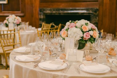 Akşam saatlerinde bir ziyafet salonunda beyaz çiçekler ve cam eşyalar sergilenir..