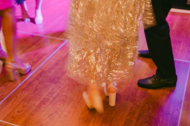 İnsanlar canlı bir etkinlikte ahşap bir zeminde dans ediyorlar. Parlak ışıklar gece boyunca neşeli bir atmosfer yaratır..