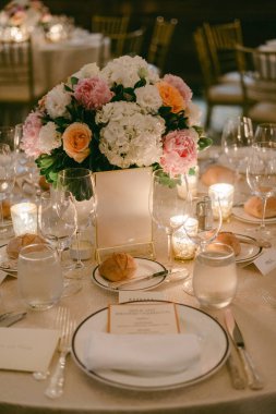 Masalar, akşam yemeği için süs eşyaları, cam eşyalar ve dürümler olan konuklar için hazırlandı..