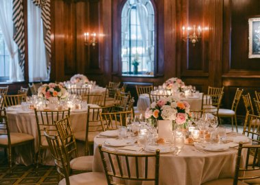 Masalar, özel bir kutlama sırasında geniş bir salonda çiçekler ve mumlarla düzenlenir..