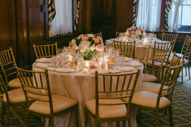 Yuvarlak masa tabaklar ve bardaklarla süslenir, bir toplantı veya etkinlik için çiçekler ve mumlarla süslenir.