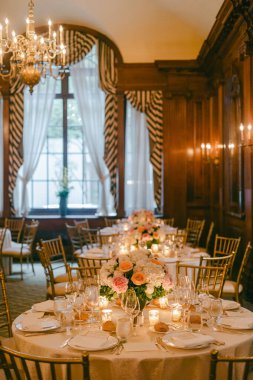 Masalar çiçeklerle ve mumlarla konukların yemek yemesi için büyük bir salonda düzenlenir..