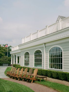 Sandalyeler büyük pencereli ve arka planda Amerikan bayrağı olan bir binanın önünde sıra sıra bekliyor..