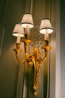 Duvar lambasında dekoratif bir armatürün üzerine yerleştirilmiş üç ışık var..