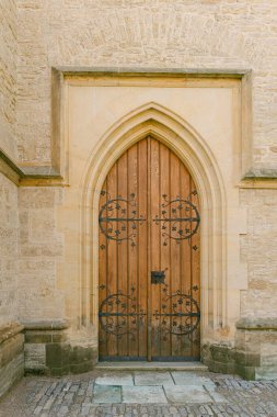 Kemerli şekilli ahşap bir kapı, tarihi mimariyi gösteren taş bir binanın üzerinde duruyor..