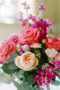 Rengarenk bir çiçek buketi güneşli bir günde bir evin masasındaki vazoda duruyor..