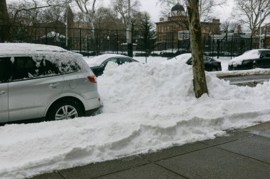 Şiddetli bir kar yağışı sonrasında kış mevsiminde şehirde bir basketbol sahasının yanındaki kaldırımlarda ve arabalarda kar birikiyor..